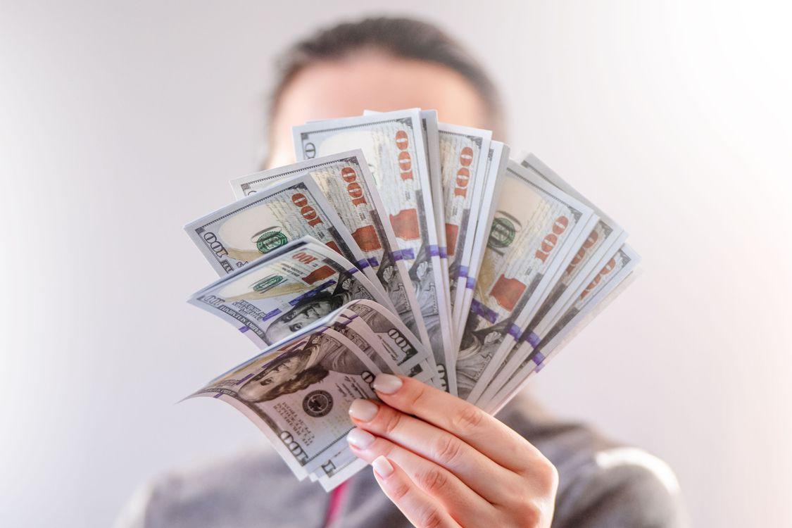 Person holding a fan of hundred-dollar bills