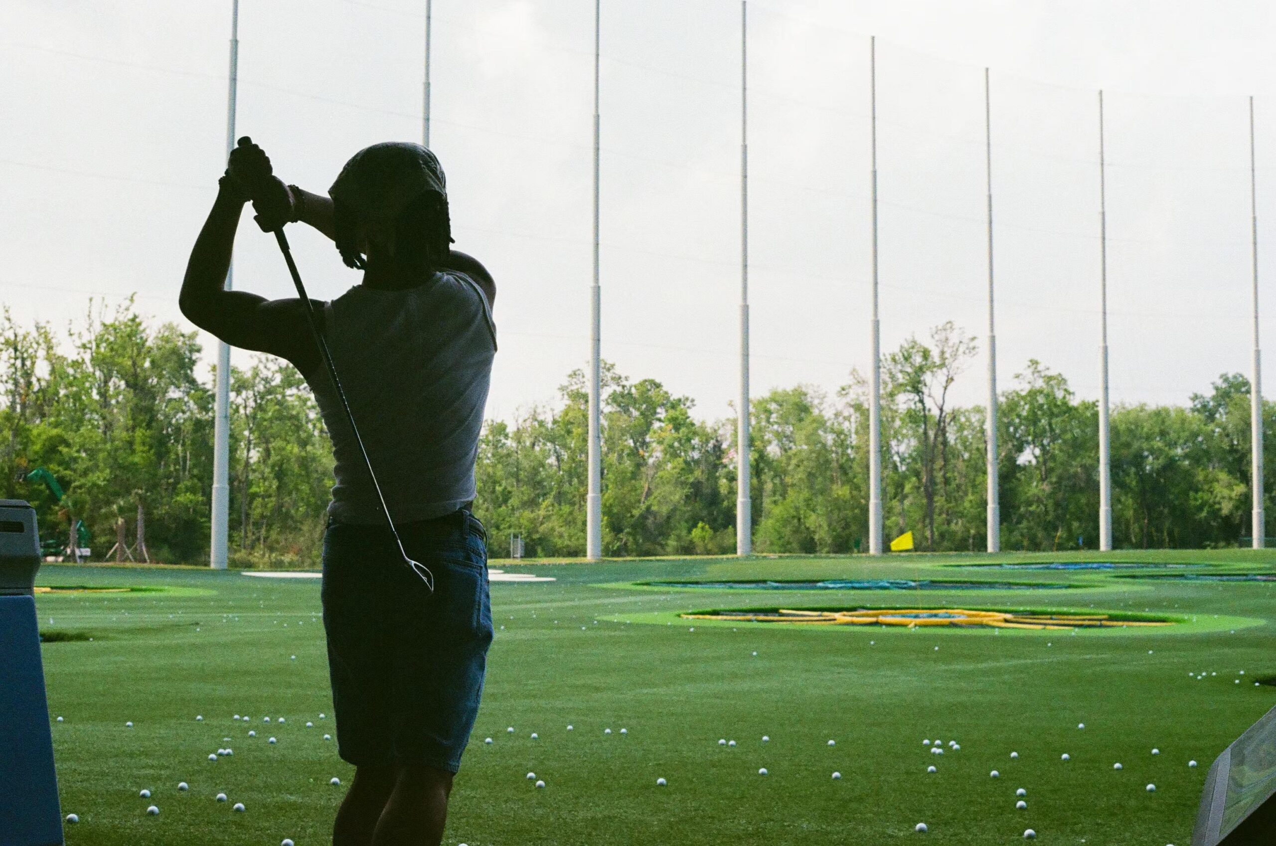 golfer-swinging-at-range Silhouette of a golfer swinging a club at a driving range