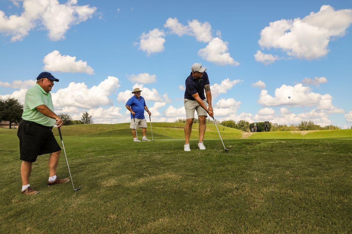 Three golfers playing on a sunny golf course