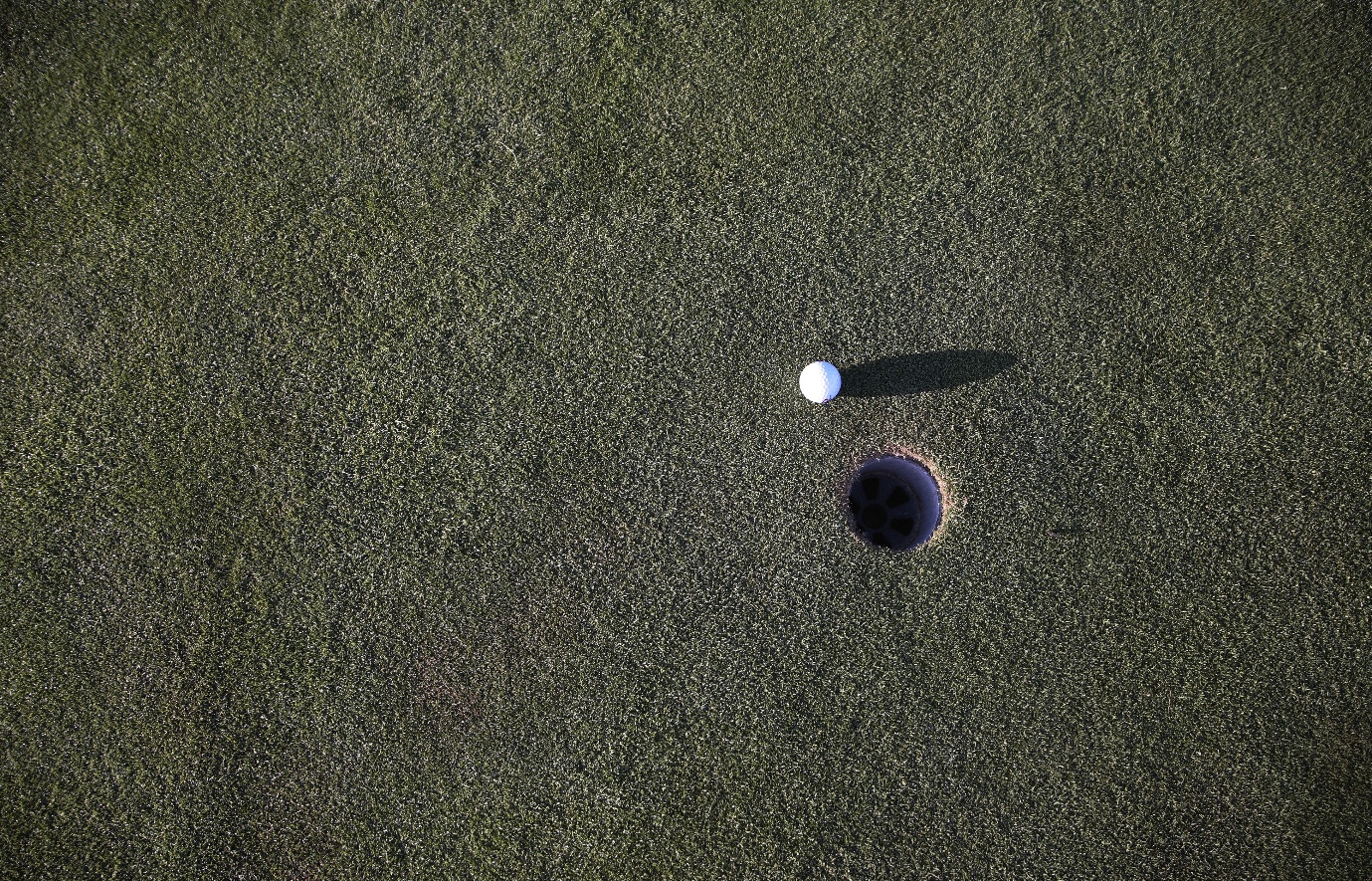A golf ball near a hole  