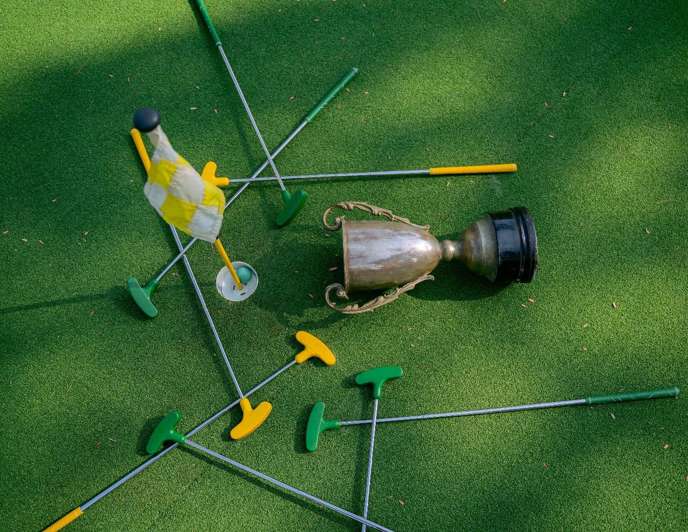 A trophy and golf clubs on grass