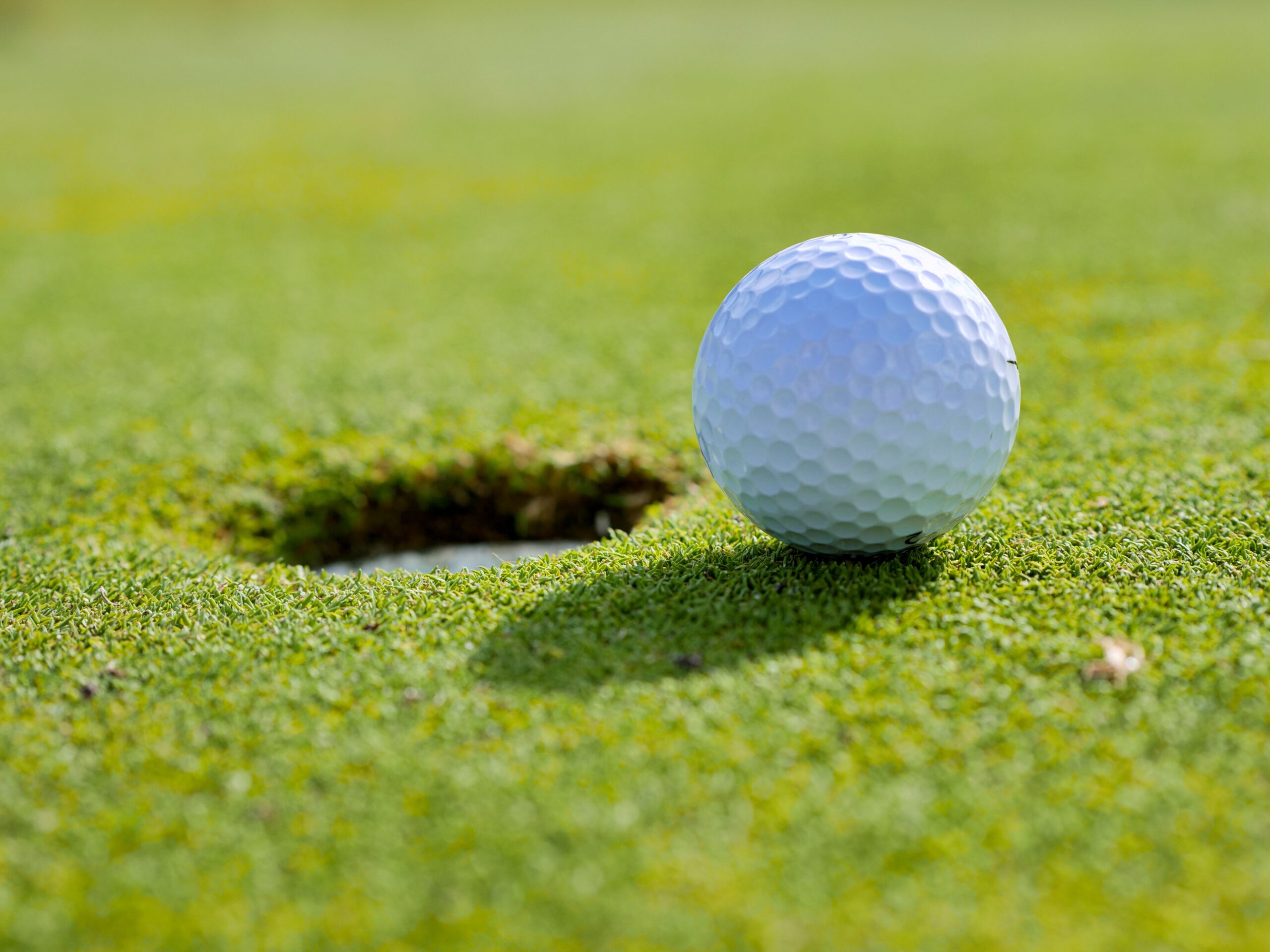 Close-up photo of a golf ball near the hole