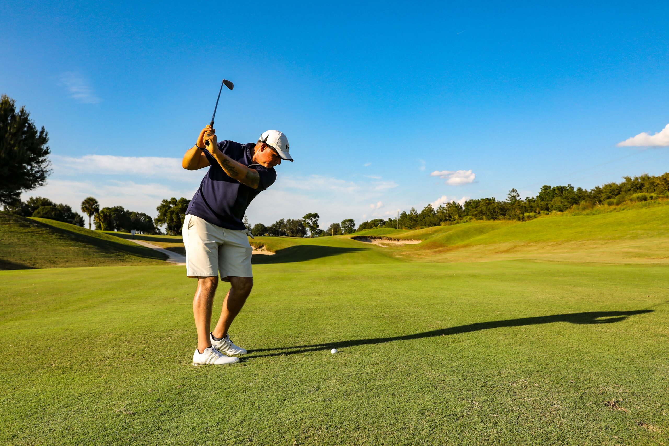 Man in a blue top playing golf on the course