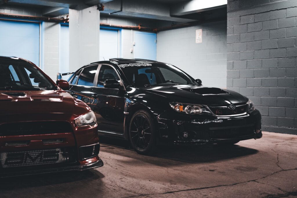Two cars parked in a garage with a black car