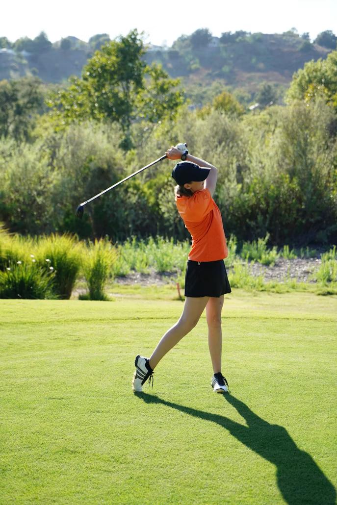 Golfer taking a shot during a dealership-sponsored tournament featuring insured hole-in-one prize opportunities.