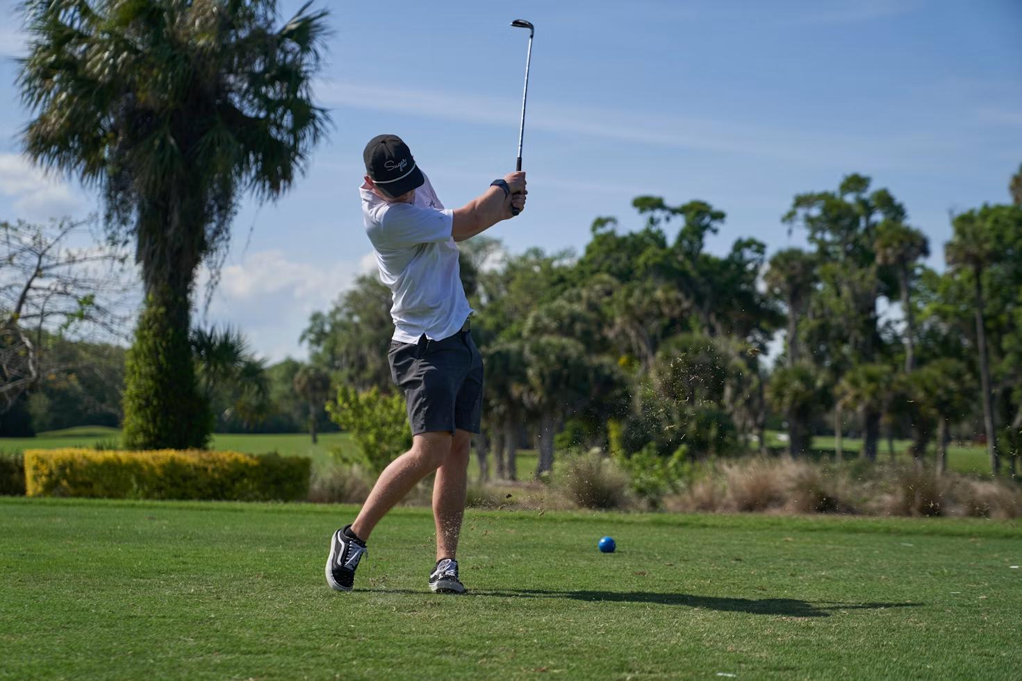 Golfer taking a tee shot on a par 3 during a tournament with golf hole-in-one insurance coverage.
