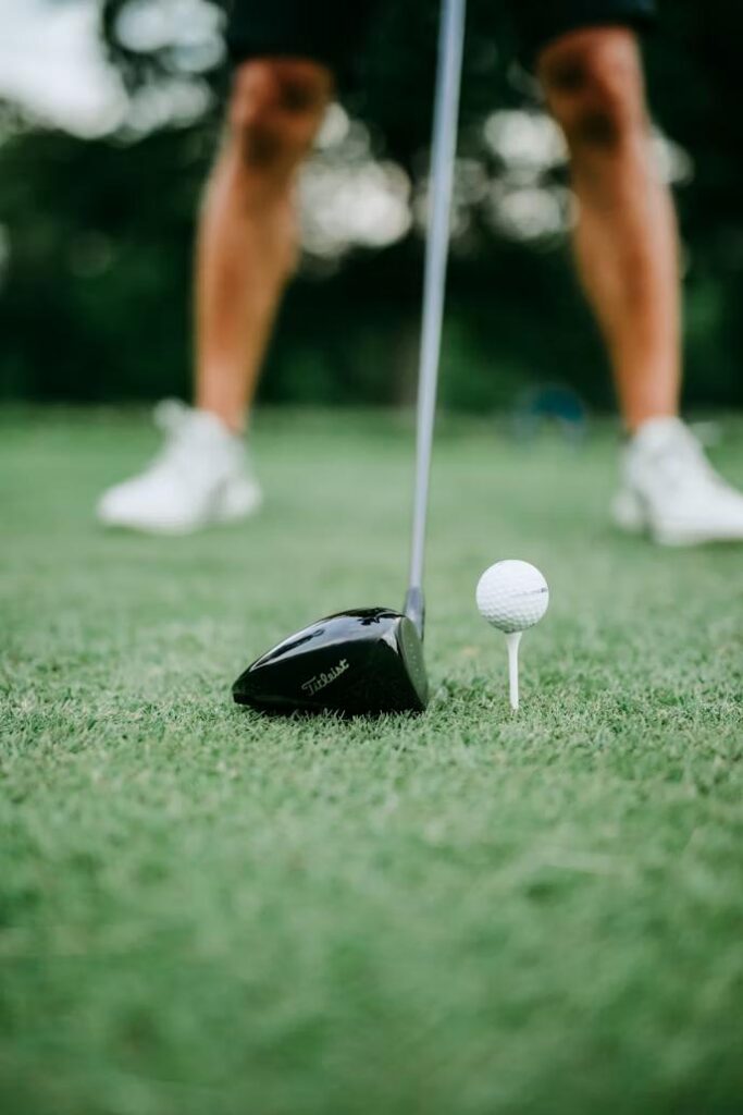 Golf ball on a tee beside a driver representing hole-in-one cash prize insurance for auto dealership golf tournament sponsorships.
