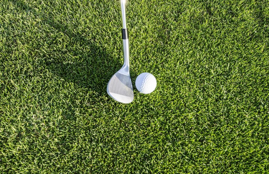 Golf club and ball on green grass representing the simple process of requesting a hole-in-one insurance quote.