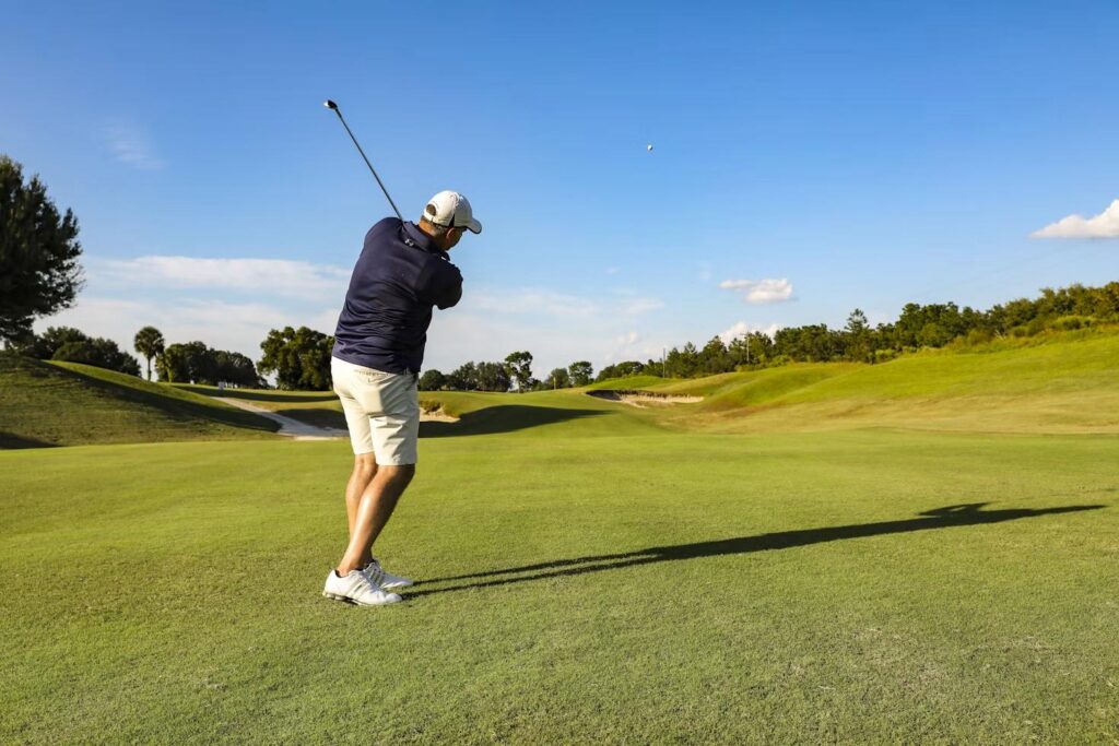 Golfer taking a shot during a tournament featuring multiple par 3 holes covered by hole-in-one prize package insurance.