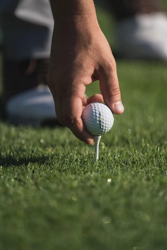 Golfer placing a ball on a tee before a million-dollar hole-in-one prize contest at a sponsored golf event.